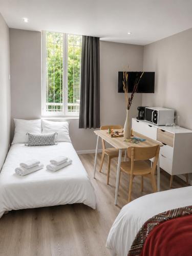 a hotel room with two beds and a table and a kitchen at LE 139 carcassonne in Carcassonne