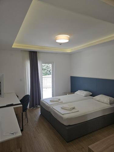 a bedroom with a bed and a desk and a window at Vile MonteMar in Herceg-Novi