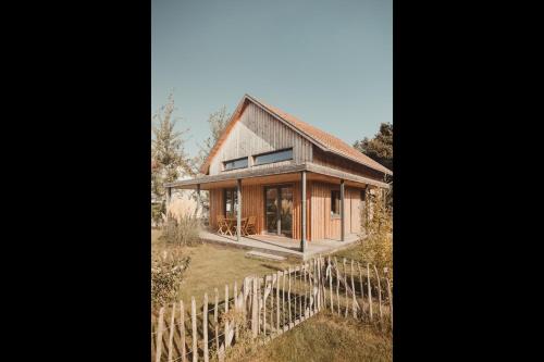 a wooden house with a fence in front of it at gemütliches Holzhaus am See in Warin
