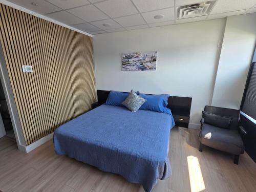 a bedroom with a blue bed and a chair at PeachView Studio 103 in Peachland