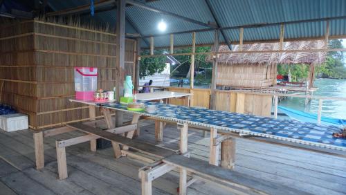 a wooden pavilion with a table and a pool at Coco Huts Guest House in Waisai