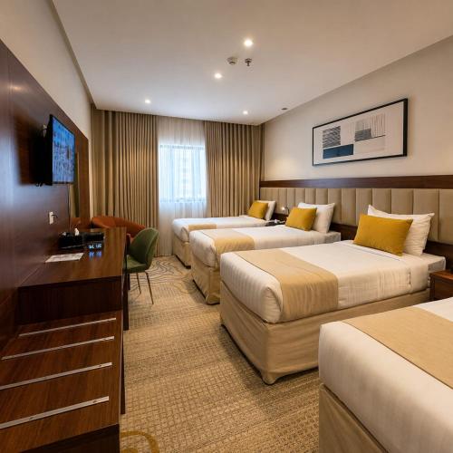 a hotel room with three beds and a television at Park Elite Hotel - فندق بارك إيليت in Mecca