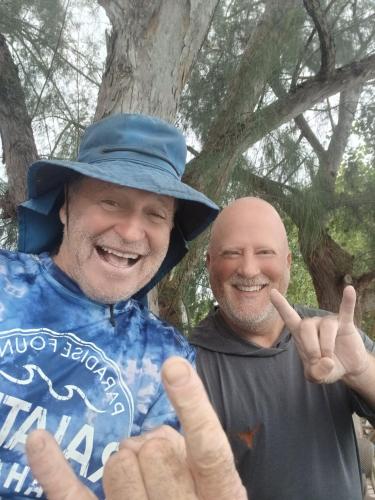 two men giving the peace sign with their hands at Voyager autrement in Moorea