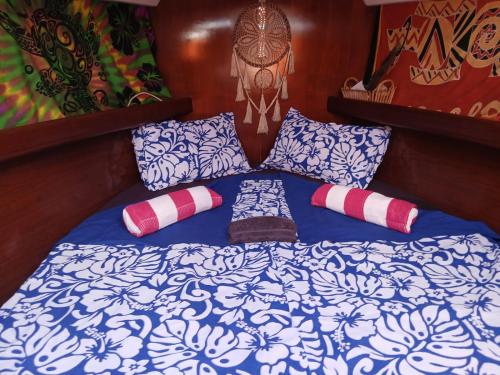 a bed with blue and white sheets and pillows at Voyager autrement in Moorea