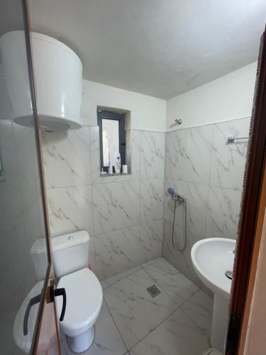 a white bathroom with a toilet and a sink at Bujtina Dalmacia 2 in Shkodër
