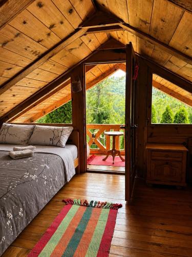 a room with a bed and a door to a patio at Drinska Villa Cabin in Perućac