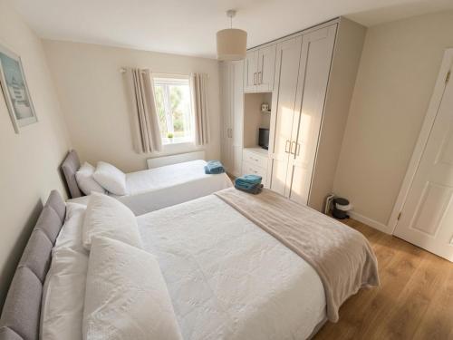 a white bedroom with two beds and a window at Cromlech Cottage in Portnoo
