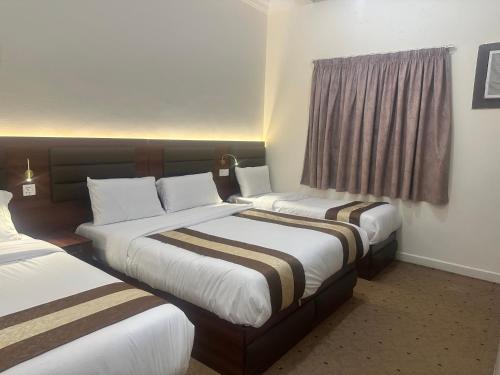 a hotel room with two beds and a window at Johraat Taba Tourist Hostel in Medina