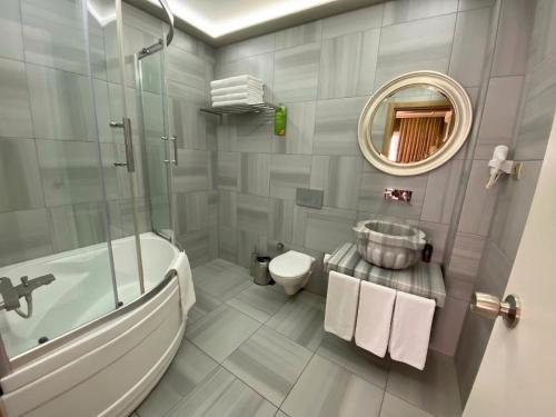 a bathroom with a tub and a toilet and a mirror at My Dora Hotel in Istanbul