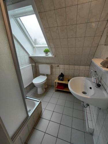 a bathroom with a sink and a toilet and a window at Ferienwohnung Laeticia in Stedesdorf