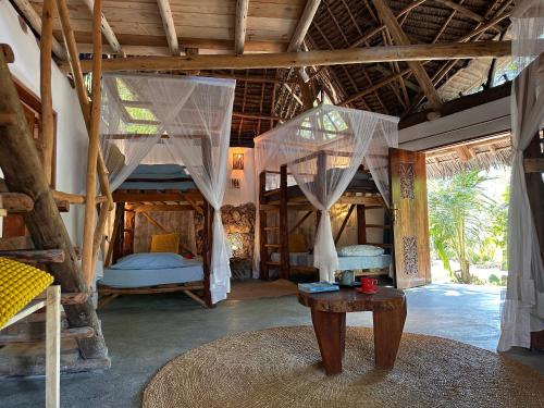 a room with two beds and a table in it at Kameleon Blue Arts Lodge in Kizimkazi