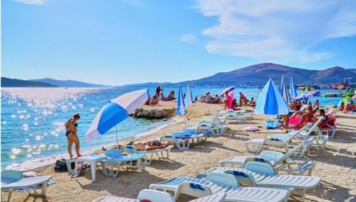 a beach with chairs and umbrellas and people on it at apartmenttwelve in Trogir