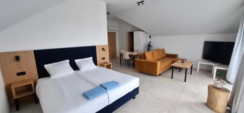 a bedroom with a large white bed and a living room at Bursztynowa Rosa & Wypożyczalnia rowerów elektrycznych in Łeba