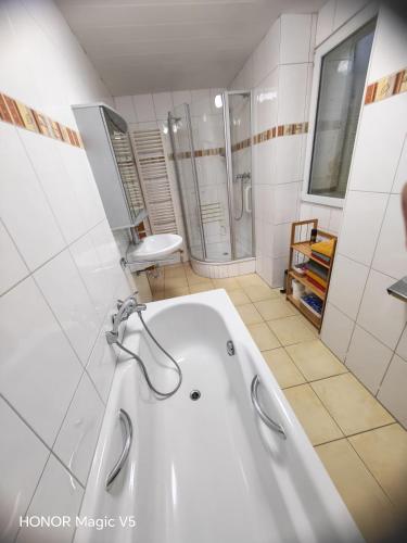 a white bathroom with a tub and a shower at Ferienwohnung Bahnhof Ehr in Halsenbach