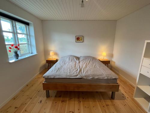 a bedroom with a bed and two lamps on two tables at Bright and quiet townhouse in Bellinge