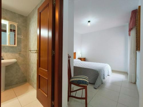 a bedroom with a bed and a bathroom with a sink at Gran Paraíso Raxo in Raxó