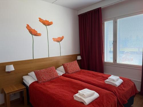 a bedroom with two beds with red sheets and flowers on the wall at Chalet in Vierumäki with golf course view in Lahti