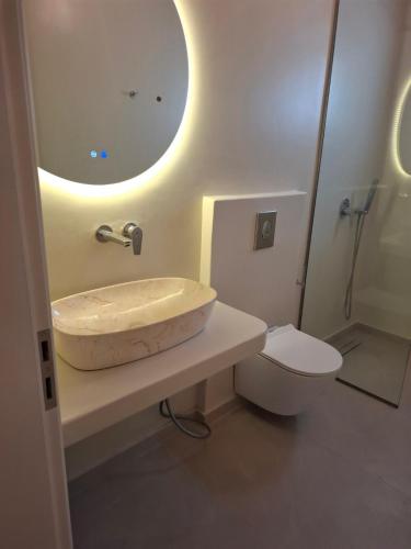 a bathroom with a sink and a toilet and a mirror at Sun & Stones Suite in Agrari