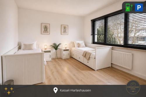 a white bedroom with two beds and a window at Ferienwohnung Kassel mit Ladesäule & Balkon in Kassel