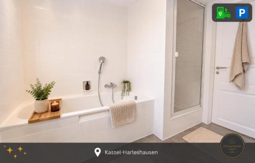 a white bathroom with a tub and a shower at Ferienwohnung Kassel mit Ladesäule & Balkon in Kassel