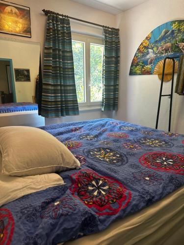 a bed with a blue blanket on it with a window at Ferienhaus mit Privatgarten in Gambarogno