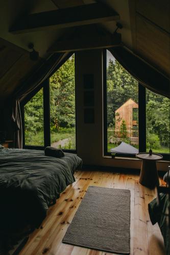 ein Schlafzimmer mit großen Fenstern, einem Bett und einem Teppich in der Unterkunft Otuli in Ćmińsk