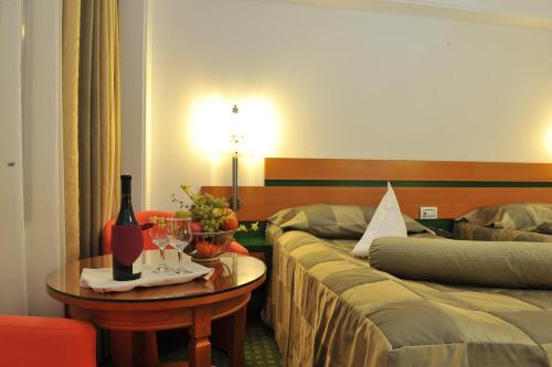 a hotel room with two beds and a table with a bottle of wine at Hotel Jasmine in Braşov
