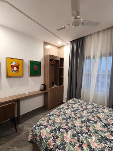 a bedroom with a bed and a desk and a window at La Villa K - 1 Studio in Lomé