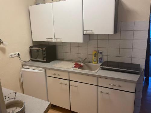 a kitchen with white cabinets and a sink and a microwave at Ferienwohnung Weinstrasse in Rostock