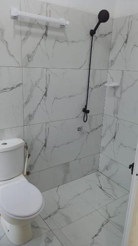 a white bathroom with a toilet and a shower at cœur d'eden in Vougomé
