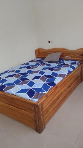 a wooden bed with a blue and white checkered mattress at cœur d'eden in Vougomé