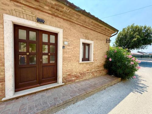 a brick house with a wooden door and a bush at Casa L Oleandro in Torrenieri