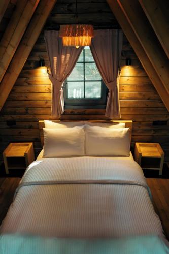 a bed in a wooden room with a window at Ötüken Dağ Evleri in Akcaabat