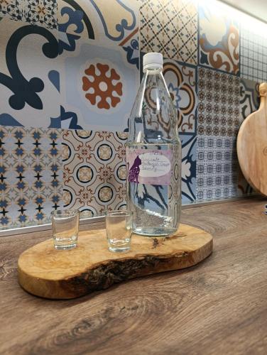 a bottle of water and two glasses on a cutting board at Pergola Garden in Nikšić