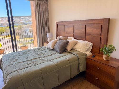 a bedroom with a large bed with a large window at Loft en Zibata con Vista Alberca y Gym in La Cañada