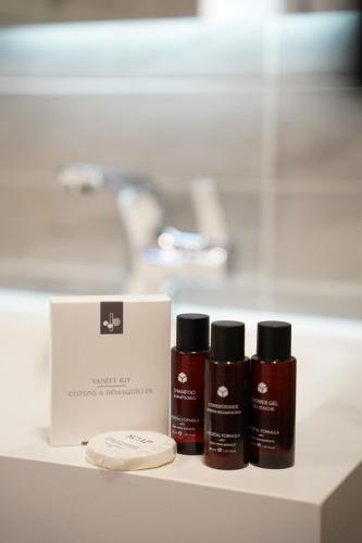 three bottles of lipstick sitting on a counter next to a box at Parkside Boutique Hotel in Prishtinë