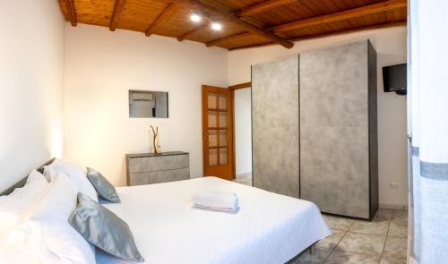 a bedroom with a white bed and a sliding door at Amò Casa in Fiumefreddo di Sicilia