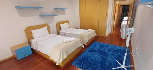 a room with two beds and a blue rug at Mansion with Swimming Pool, Pool Table & GrillArea in Braga