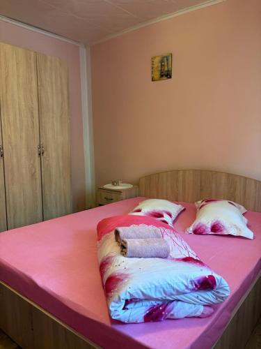 a bed with pink sheets and pillows on it at Apartament Iulia in Orşova