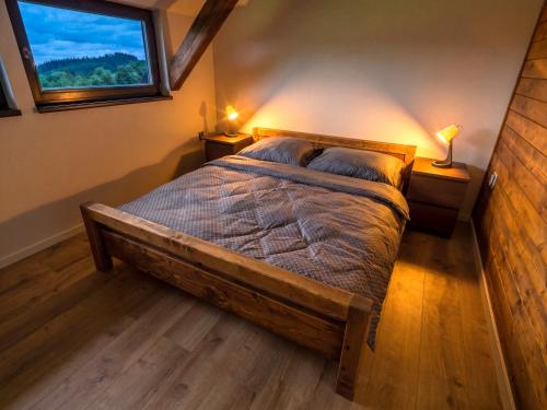 a bedroom with a wooden bed with a window at Apartmán pod Pustým vrchem in Říčky