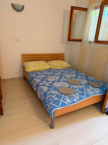 a bedroom with a bed with a blue comforter and yellow pillows at Apartman Luka Pogled na more in Neum