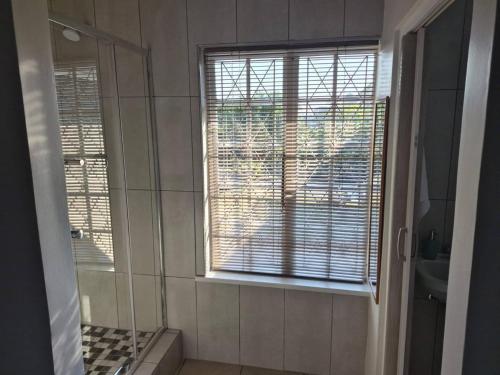a bathroom with a shower and a window with blinds at Nombelas Cottage in Westville
