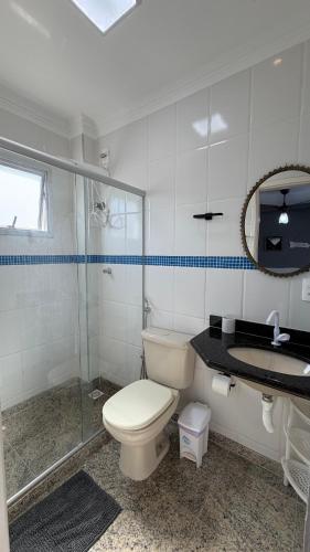 a bathroom with a toilet and a shower and a sink at Cobertura de Frente Para o Mar e Piscina Village das Ondas in Piúma