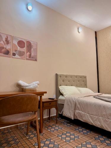 a bedroom with a bed and a table and a chair at Pousada Nhá Luz in Salesópolis