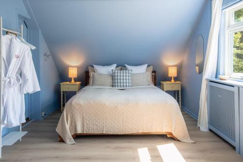 a blue bedroom with a bed and two lamps at Hotel Villa Lejet in Tisvilde