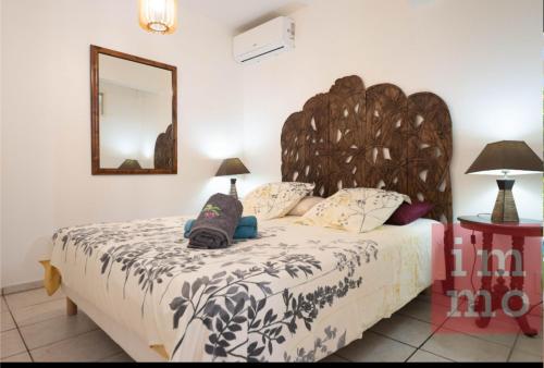 a bedroom with a large bed with a large wooden headboard at Kaz'Iguan in Saint-François
