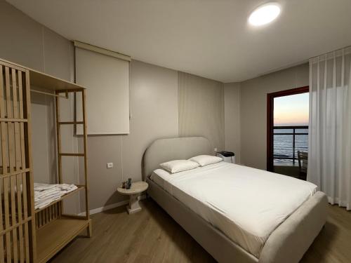 a bedroom with a large white bed and a window at קו המים - Waterline סוויטות עם גקוזי הכי קרוב לים in Netanya