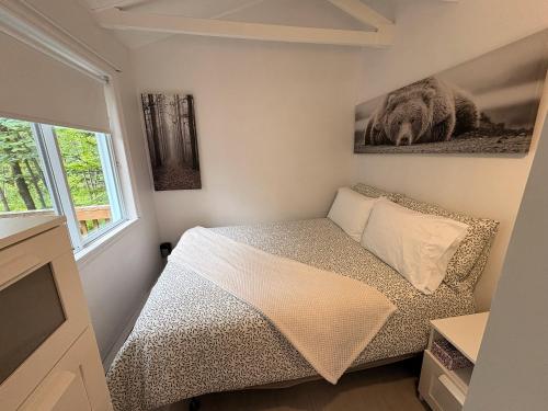 a small bedroom with a bed and a window at L'Opie in Saint Adolphe D'Howard