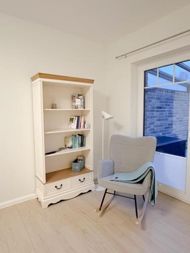a white room with a chair and a book shelf at Ferienwohnung Knut in Bornholt