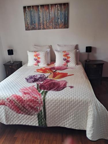 a bed with a white comforter with flowers on it at Casa Sequeira in Fajã da Ovelha